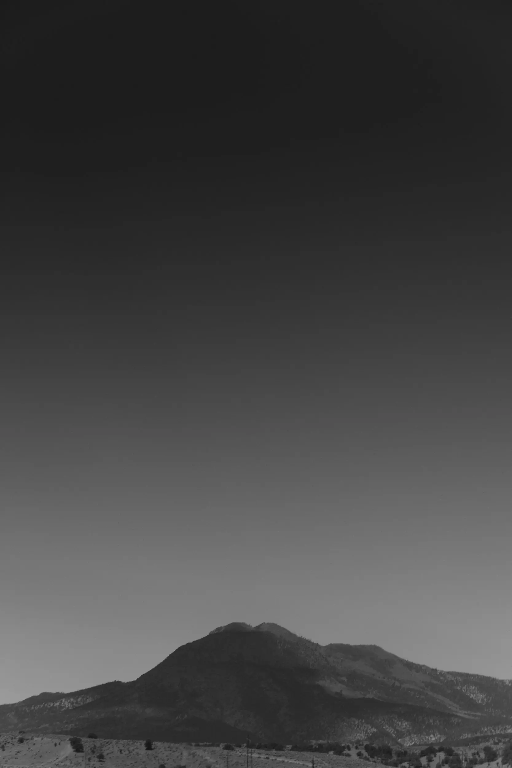 Black and white shadowed hill underneath a dark sky.